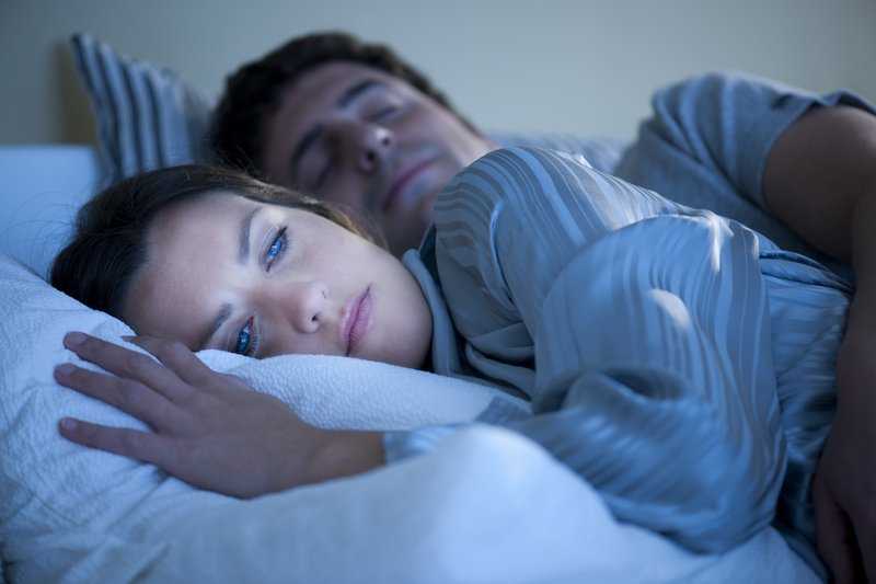 Frau liegt wach mit Schlafmangel im Bett